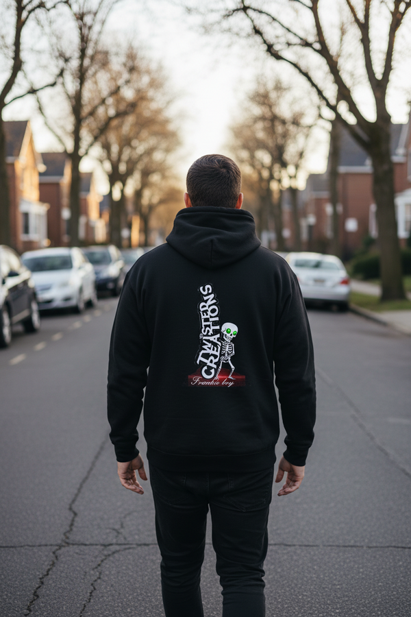Person wearing a black hoodie with a graphic design on the back, standing on a residential street.
