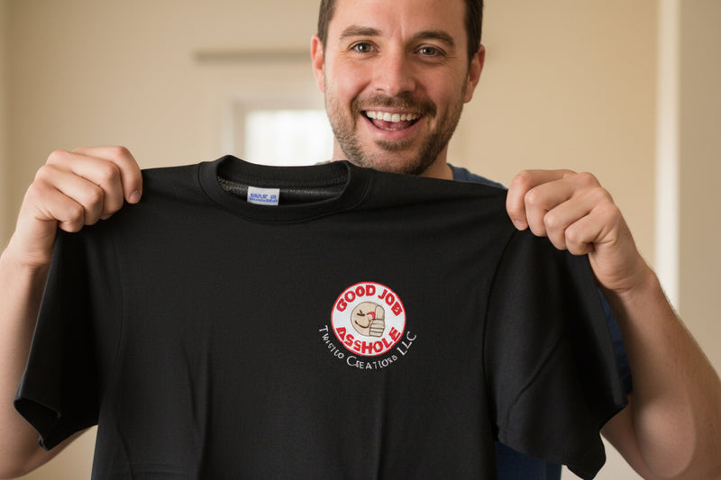 Man hoplding up a black t-shirt with a logo and text, smiling.