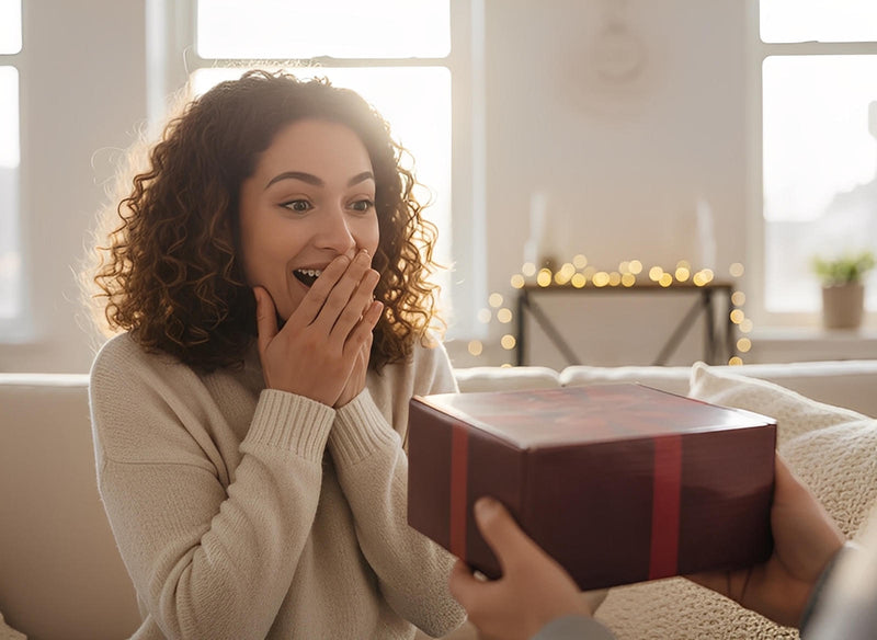 Excited woman surprised by receiving a gift box representing The Best Friend Candle PG-13 gift-ready candle box