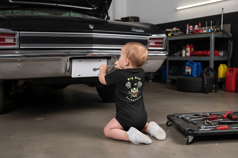 Child in a garage next to a classic car, wearing a black t-shirt with graphics.