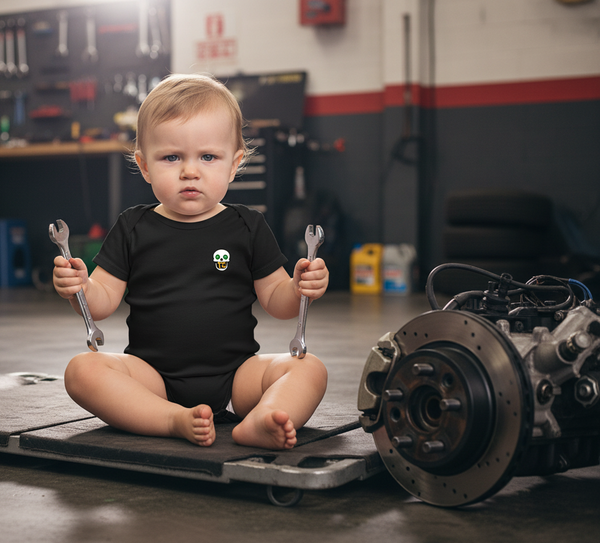 Child in a garage holding wrenches with car parts in the background